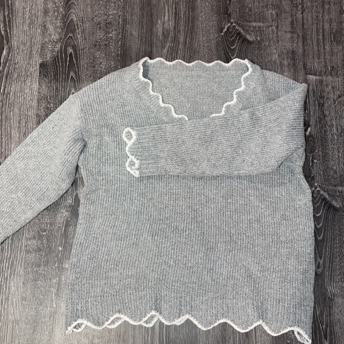 Grå stickad tröja med vågig kant