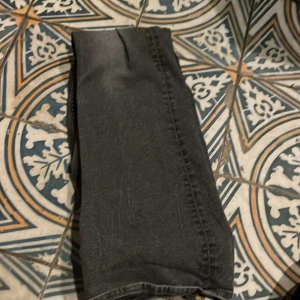 Gråa jeans  - Snygga svarta jeans med en klassisk design. De har en knapp och dragkedja framtill samt fickor både fram och bak. Perfekta för en stilren look.