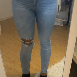 Blå skinny jeans med slitning - Snygga blå skinny jeans med slitningar på knäet. Jeansen är högmidjad och i storlek S.