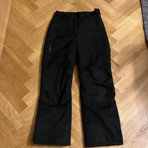 Svarta vinter byxor från On The Peak - Säljer ett par svarta vinterbyxor från On The Peak. Byxorna har en praktisk design med flera fickor och justerbar midja. Perfekta för utomhusaktiviteter och håller dig varm under skidåkningen 