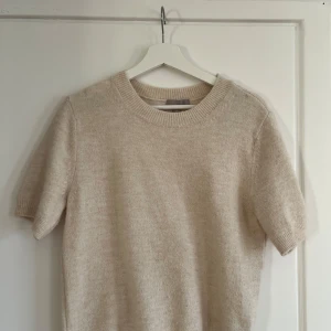 Stickad t-shirt - Säljer en stilren beige tröja från H&M i storlek S. Tröjan är kortärmad och har en rund halsringning. Fint skick endast använd ett fåtal gånger💗