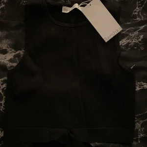 Svart ribbad linnetopp från Bershka - Otroligt fin topp från Berskha och som är i nyskick då den är helt oanvänd!! Storleken är L men är definitivt en M då den är liten i storlek, super söt på men tyvärr inte min storlek 🖤 Skriv till mig om ni är intresserade!!  Vid snabbt köp kan jag tänka mig att sänka priset !