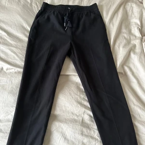 Varma kostymbyxor - Snygga varma kostymbyxor från H&M med elastisk midja och snörning. Byxorna har en rak passform, har vek framtill och mini slits. Använda några få gånger.