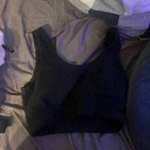 Svart ribbad linnetopp från Oxide - Snygg svart ribbad linnetopp från Oxide i storlek S. Perfekt för en stilren och bekväm look. Toppen har en enkel design med breda axelband och rund halsringning. Den sitter bra när du springer. Använd 1-3 gånger men är noggrant tvättad! 