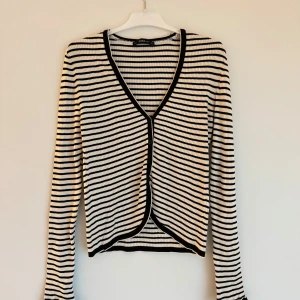 Randig ribbad tröja från Zara - Säljer en snygg svartvit randig tröja från Zara. Den är ribbad med en v-ringad design och långa ärmar. Perfekt för en stilren look.