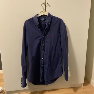 Blå skjorta från Polo Ralph Lauren - Snygg blå långärmad skjorta från Polo Ralph Lauren. Perfekt för en stilren look. Storlek M, bra skick! Pris kan diskuteras vid snabb affär🤩