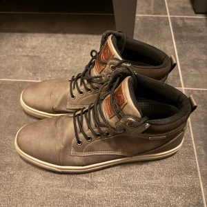 Grå vattentäta sneakers från Linear - Hej! Säljer dessa grå sneakers från Linear med svart snörning och bruna detaljer. Skorna är vattentäta och har inga hål i sulorna eller i hälkappan.  De har använts väl och har endast lite slitage på ovansidan vilket ses på bilderna.  Hör av er vid frågor!