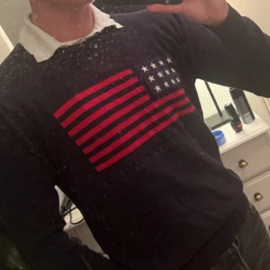 Svart tröja med amerikanskt flaggmönster från GANT - Snygg svart tröja från GANT med ett iögonfallande amerikanskt flaggmönster i rött och vitt på bröstet. Perfekt för en stilren och avslappnad look. Ps har vuxit ur den och rensade garderoben o hittade den😁