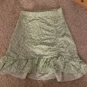 Grön blommig kjol från Gina Tricot - Söt grön kjol med blommigt mönster från Gina Tricot med volanger längst ner. Jättefin till sommaren med gulligt mönster