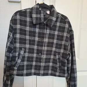 Svart rutig kappa - Höstig kappa som är i nyskick. Använf fåtal gånger. Säljer för att den inte kom till användning och nu är den för liten. Croppad modell.