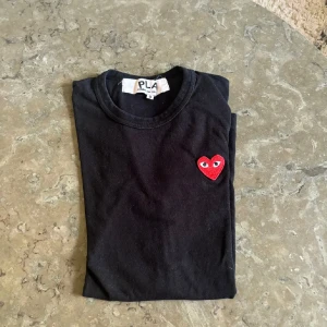 Svart t-shirt med rött hjärta - Säljer en svart t-shirt från cdg/ Play Den är kortärmad och gjord i mjukt bomullsmaterial. 