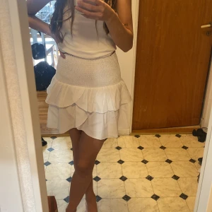 Volang kjol  - En härlig vit kjol, fint att ha som den är eller som en söt topp. Aldrig använd, i nytt skick. Sitter skönt runt kroppen! Ord pris 500kr