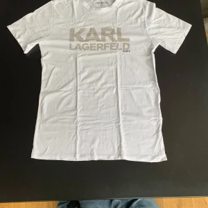 KARL LAGERFIELD T-SHIRT⚪️ - NYPRIS: 999kr VÅRT PRIS: 319kr! Säljer en Karl Lagerfeld T-Shirt i nyskick, 10/10! Perfekt en vit t-shirt som passar till allt. Kontakta vid eventuella frågor. Kan sänka priset vid snabb affär 💪!