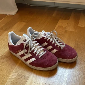 Adidas Gazelle i röd mocka - Säljer mina vinröda adidas gazelle skor, så så snygga men de kommer tyvärr inte till användning. Jag har använt de fåtal gånger och därav små smuts defekter på sulan men annars fina och fräscha! Skriv för fler bilder och buda gärna 💓