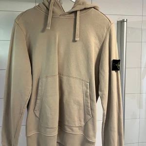 Stone Island hoodie, beige - Säljer en stilren beige Stone Island hoodie med känguruficka och justerbar huva. Perfekt för en avslappnad look. Någon slags missfärgning på vänster axel (se bild 2), men inget som syns supermycket. Storlek S, men passar även XS och M. Nypris 3000-4000 kr. Mitt pris 550 kr. Hör av er vid frågor. //Ludde