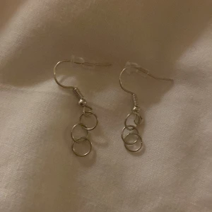 Silverfärgade örhängen med ringar - Snygga och stilrena silverfärgade örhängen med tre små ringar i rad. Perfekta för att ge en elegant touch till din outfit. Lätta att bära och passar till många olika stilar.