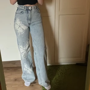 Jeans med fjärilsmönster  - Snygga jeans från H&M med ett unikt fjärilsmönster. Byxorna har en hög midja och en loose passform som ger en avslappnad stil. Perfekta för att ge din outfit en cool touch.