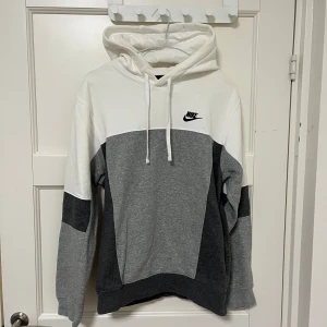 Nike hoodie - Nike hoodie i vit och grå färger. Storlek M och i bra skick bortsett från en pytteliten fläck snett vänster om det broderade nike märket på bröstet