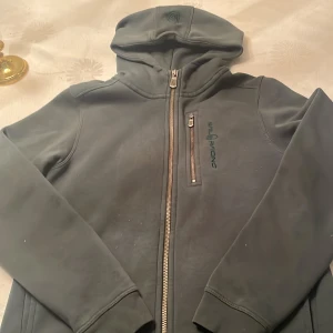 Mörk grön ziphoodie från Sail Racing, storlek 160 - Snygg mörk grön huvtröja från Sail Racing med dragkedja och huva.
