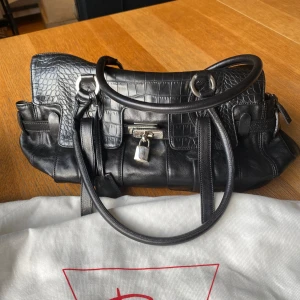 Detaljrik svart handväska  - Så cool väska med supersnygga detaljer & praktiska innerfack, silvriga detaljer utantill och guldigt silkesliknande tyg inuti💞