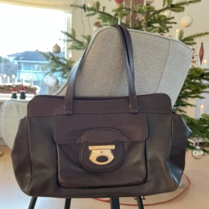 Brun skinnväska från Tod's - Snygg brun skinnväska från Tod's med gulddetalj på framsidan. Väskan har två handtag och en praktisk innerficka med dragkedja. Skriv för fler frågor eller bilder!❤️