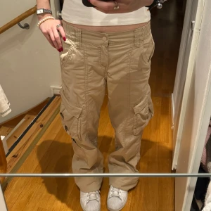 Cargo byxor  - Beiga cargo byxor från H&M. Säljer då de inte används och inte är min stil! Är 155 cm lång men byxorna är betydligt längre än vad de ser ut som på bild (de är vikta) 🩷🙌 innersbenlängden - 75.5cm ,  midjemått (mätt platt korsöver) - 34cm men midjan är väldigt stretchig, grenlängden - 23cm priset kan diskuteras & använd gärna köp nu knappen 🤗💕
