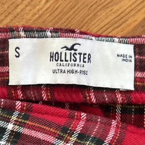Rutig röd kjol från Hollister - Snygg rutig kjol i rött från Hollister med hög midja. Kjolen är kort och har en klassisk design:)
