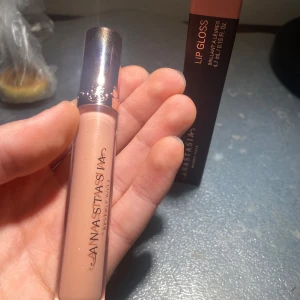 Läppglans från Anastasia i Cantaloupe Original pris 200 sek - Snyggt läppglans från Anastasia i en ljus nude nyans. Förpackningen är elegant med en metallisk kork och märkeslogga. Perfekt för en glansig finish. Den är helt ny, helt otestad, kommer med förpackning såklart, har online kvitto såklart