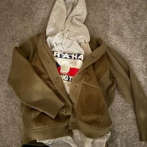 Soft brun kofta - Säljer en brun stickad kofta med knappar och en mocka detalj på framsidan. Riktigt snygg och skön till de kyligare dagarna. Storlek Large passar mig perfekt som är 185cm 85kg