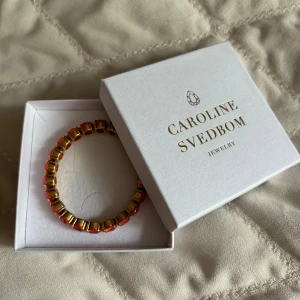 Färgglatt armband från Caroline Svedbom - Säljer ett superglittrigt armband från Caroline Svedbom. Det har en härlig mix av rosa och guldiga pärlor som verkligen poppar! Perfekt för att liva upp vilken outfit som helst. Kommer i originalförpackning. Gummibandsform och passar alla handleder. Nypris 995kr