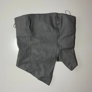 Grå topp - Grå topp från Bershka som aldrig är använd. Croppad och utan axelband. Silvrig dragkedja.