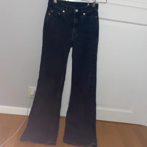 Svarta bootcut jeans från Glow - Säljer ett par snygga svarta bootcut jeans från Glow. De har en klassisk femficksdesign med knappar och dragkedja fram. Perfekta för både vardag och fest!