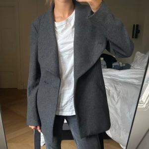 Kappa - Grå kappa från stockh lm. Väldigt bra skick då den ej har använts mycket. Dock har en knapp lossnat (vilket syns i bild) men detta borde kunna sys på enkelt💗 Den har dessutom innerfickor