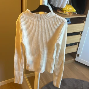 Vit ribbad tröja från H&M Divided - Säljer en stilren vit ribbad tröja från H&M Divided. Tröjan har långa ärmar och en hög krage som ger en snygg look. Perfekt för kyligare dagar. Passar bra till både jeans och kjol. Den är även tight och formas fint utifrån kroppen!