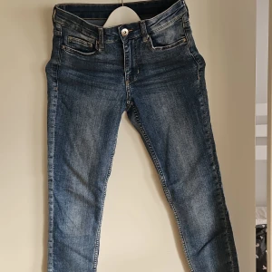 Blå jeansbyxor - Snygga blå jeansbyxor med en klassisk femficksdesign och knappgylf. De har en smal passform och är perfekta för en avslappnad stil. Jeansen har en lätt tvättad look som ger dem en trendig touch.
