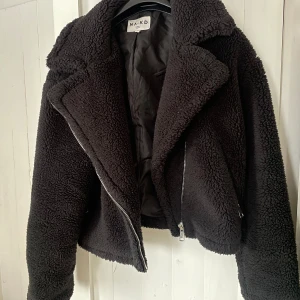 Svart teddyjacka från NA-KD - Mysig svart teddyjacka från NA-KD med dragkedja framtill. Jackans ärmar har även en dragkedjedetalj, den är lite croppad i modellen och använd typ en höst, så sparsamt använd 💕