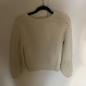 Vit stickad tröja - Säljer en stilren vit stickad tröja med långa ärmar och ett diskret hålmönster längs ärmarna ger en mysig känsla. Passar bra till både jeans och kjol.