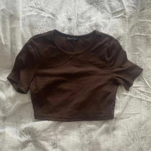 Brun croppad t-shirt från Shein - Säljer en brun croppad t-shirt från Shein. Den har korta ärmar och en rund halsringning. Perfekt för en avslappnad stil.