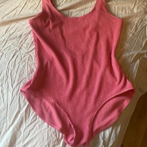 Rosa baddräkt från Monki - Säljer en snygg rosa baddräkt från Monki med ribbad textur. Den har en djup v-ringning i ryggen och breda axelband. Perfekt för sommarens alla badäventyr! 💖