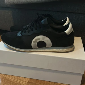  Oliver Cabell daybreak - Snygga svarta sneakers från Oliver Cabell med vita detaljer och snörning. Skorna har en stilren design med en vit sula och en diskret logga på hälen. Perfekta för en casual look. Skick 10/10 då dem bara är lite smutsiga men kan lätt få dem som helt nya. Änvända ca 20 gånger. Allt og medföljs. 44 men passar även 43