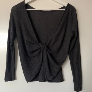 Svart backless topp - Snygg svart ribbad topp med lång ärm och djup v-ringning baktill.