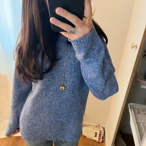 Blå stickad tröja - Säljer en mysig blå stickad tröja med långa ärmar. Perfekt för kyliga dagar och passar bra till jeans. Tröjan har en enkel och stilren design som gör den lätt att matcha med olika accessoarer.