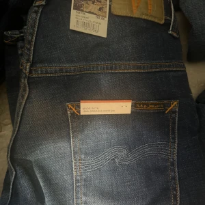 Blå jeans från Nudie Jeans w30L36 - Snygga blå jeans från Nudie Jeans i en klassisk straight stil. Tillverkade av 100% ekologisk bomull med en autentisk tvättad look. Perfekta för en avslappnad stil med fem fickor och knappgylf.