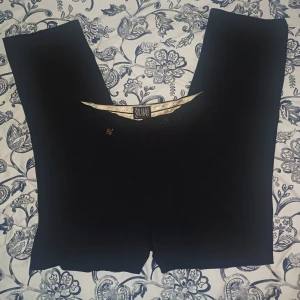 Svarta byxor från S.Oliver - Snygga svarta kostymbyxor från S.Oliver med en klassisk design. Perfekta för en stilren look. Byxorna har en rak passform. Köpta secondhand 