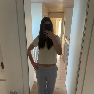 Vit stickad kortärmad topp - Säljer en stilren vit stickad kortärmad topp. Toppen har en enkel design och är lätt att matcha med olika outfits. Toppen är i gott skick och har endast används några fåtal gånger!