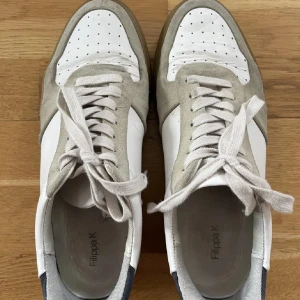 Sneakers från Filippa K i mocka och skinn - Snygga sneakers från Filippa K i en stilren design med vit och beige färgkombination. Skorna har snörning och är tillverkade i en mix av mocka och skinn. Perfekta för en avslappnad och trendig look.