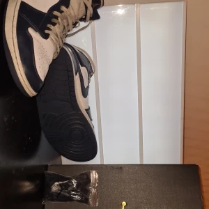Air Jordan 1 Mid 'White Metallic Gold Obsidian' - Säljer ett ett par Jordan 1 Mid som är helt okej använda och perfekt form! Skorna köpte jag för 2700 nu finns dem här till salu Lite smutsiga men går att få bort 