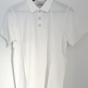 Vit pikétröja från Burberry - Säljer en stilren vit pikétröja från Burberry med klassisk krage, ny och oanvänd. Perfekt för en avslappnad men elegant look. Tröjan har en diskret textur och är i en tidlös design. Perfekt för svenska sommaren.