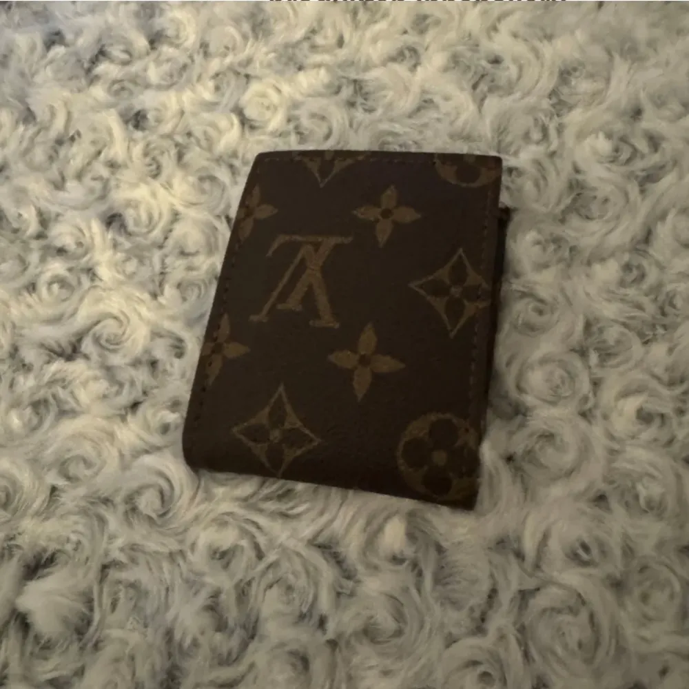 Snygg brun plånbok med det klassiska monogrammönstret. Plånboken har flera fack för kort och sedlar, perfekt för att hålla ordning på dina tillhörigheter. En stilren accessoar för den modeintresserade.. Laukut & Käsilaukut.