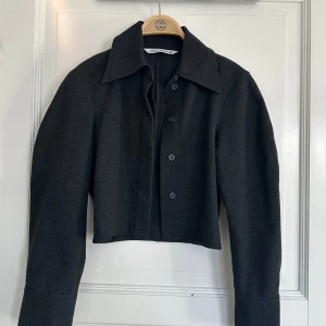 Svart croppad jacka från Zara - Snygg svart croppad jacka från Zara med knappar framtill. Den är mörk grå 🩶